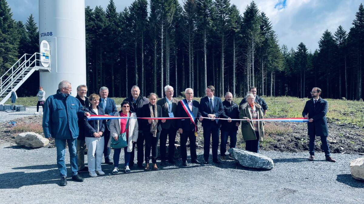 Un groupe de personne devant une éolienne qui coupe un ruban d'inuaguration