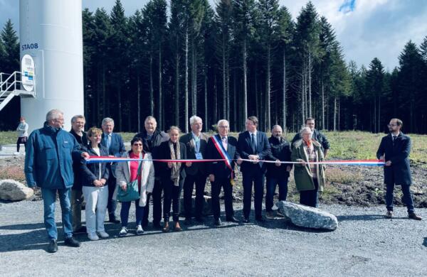 Un groupe de personne devant une éolienne qui coupe un ruban d'inuaguration