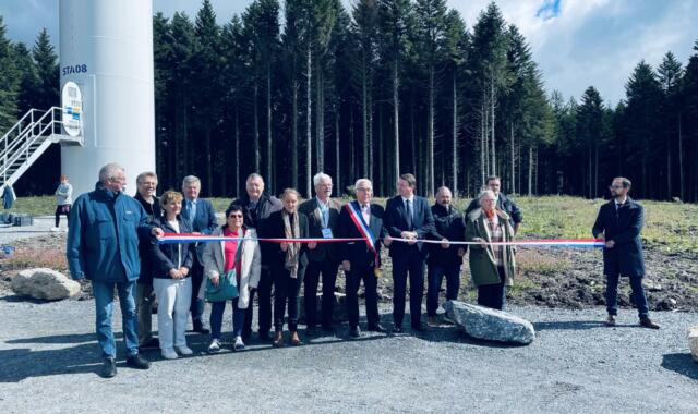 Un groupe de personne devant une éolienne qui coupe un ruban d'inuaguration