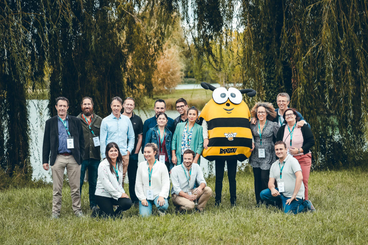 Un groupe de personne qui pose à côté d'une mascotte d'abeille