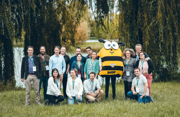 Un groupe de personne qui pose à côté d'une mascotte d'abeille