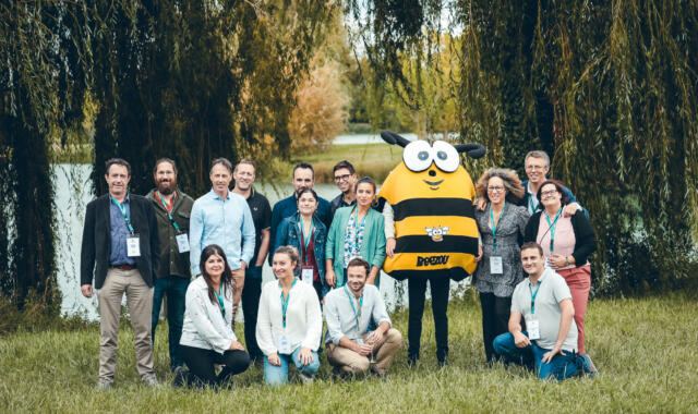 Un groupe de personne qui pose à côté d'une mascotte d'abeille